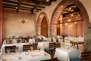 Innenansicht des Restaurants im Rixos Bab Al Bahr Hotel mit runden Bögen und Steinwänden.