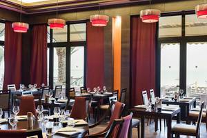 Restaurant des Rixos Bab Al Bahr Hotels mit Tisch, Gläsern und Ausblick auf den Ozean.