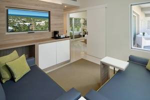 Wohnzimmer des Grand Sirenis Punta Cana Resort mit zwei blauen Sofas, Fernseher und Tisch