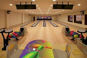 Bowlinghalle im Hotel Dreams Royal Beach Punta Cana mit Bowlingbahnen, Bowlingkugeln und Monitoren.