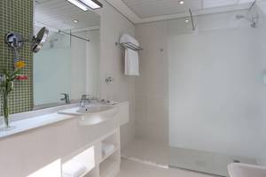 Badezimmer im TRYP by Wyndham Abu Dhabi City Center mit weißer Einrichtung, Spiegel und Dusche.