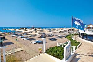 Club Nena Hotel Strand mit Sonnenschirmen und Liegestühlen unter blauem Himmel