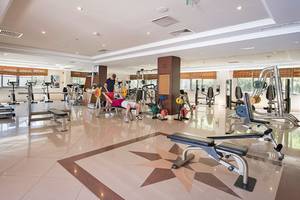 Fitness-Center im Hotel Club Nena mit verschiedenen Geräten und Menschen, die trainieren.