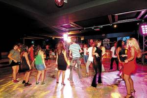Leute tanzen in der Club Nena Nachtclub, einige mit High Heels und anderen in lässiger Kleidung.
