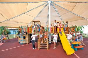 Familien und Kinder spielen auf einem überdachten Spielplatz im Club Nena.