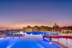 Abendstimmung am Pool im Club Nena Resort mit blau beleuchteten Wasser und Sonnenliegen