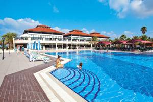 Club Nena Hotel zeigt eine große Schwimmbadanlage mit Gästen vor dem Gebäude.