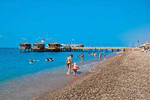 Familie am Strand vor dem Club Nena Hotel mit Steg und Sonnenschirmen
