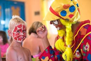 Ein Clown malt das Gesicht eines Jungen im Club Nena Hotel.