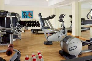 Fitnessstudio im Mykonos Grand Hotel mit verschiedenen Geräten und einer gespiegelten Wand.