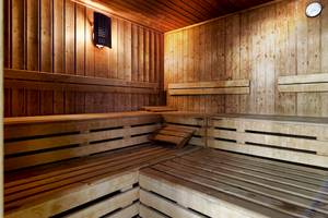 Innenansicht der Sauna im Bull Dorado Beach & Spa Hotel mit Holzbänken und einer Wanduhr.