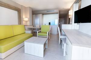 Inneneinrichtung eines Hotelzimmers im Bull Dorado Beach & Spa Hotel mit gelbem Sofa, Tisch und Fernseher.
