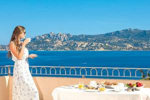 Frau genießt Frühstück auf dem Balkon im Resort Cala Di Falco mit Meerblick