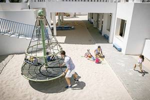 Kinder spielen im Sand mit einem Kletternetz im Robinson Djerba Bahiya Hotel.