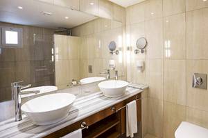 Das Badezimmer des Robinson Djerba Bahiya Hotels mit zwei Waschbecken, Spiegeln und einem Toilettensitz.