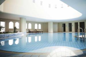 Innenpool des Robinson Djerba Bahiya Hotels mit blauen Fliesen und Loungemöbeln.