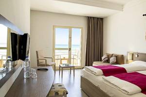 Doppelzimmer im Robinson Djerba Bahiya Hotel mit Meerblick, zwei Betten, Fernseher und Wasserflaschen auf dem Schreibtisch.