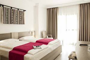 Zimmer im Robinson Djerba Bahiya Hotel mit zwei Betten, Dekor und Möbeln.