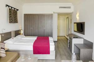 Ein modernes Hotelzimmer im Robinson Djerba Bahiya mit Doppelbett, Nachttischen, Fernseher und Kleiderschrank.