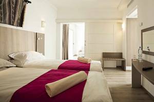 Zwei Doppelbetten mit roten Decken in einem Hotelzimmer im Robinson Djerba Bahiya.