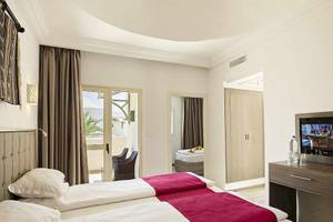 Zimmer im Robinson Djerba Bahiya Hotel mit zwei Betten, Fernseher und einem Schreibtisch.