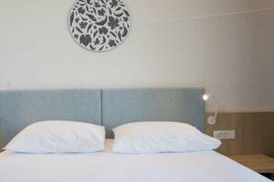 Doppelbett im Hotelzimmer von Osmine Slano mit weißen Kissen und blauen Kopfteilen.