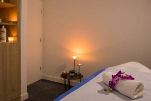 Spa-Behandlungsraum im Osmine Slano Hotel mit Massagetisch, Kerzen, Blumen und Pflegeprodukten.