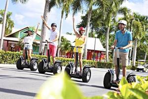 Vier Personen auf Segways fahren lächelnd im Freizeitpark.