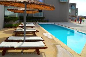 Akti Palace Hotel mit Pool und Liegestühlen, Familie im Hintergrund.