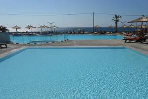 Zwei Swimmingpools am Akti Palace Hotel mit Blick auf das Meer und Liegestühlen.