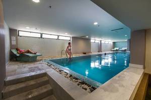 Ein mädchen steht im innenpool des akti-palastes und ein anderes mädchen liegt auf einer liege