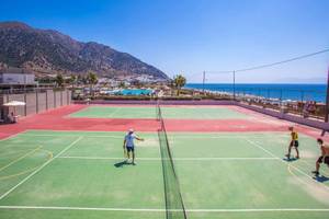 Tennisplätze am Strand des Akti Palace Hotels mit Spielern und Blick auf das Meer.