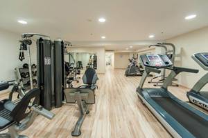 Fitnessbereich im Akti Palace Hotel mit verschiedenen Trainingsgeräten und Holzboden.