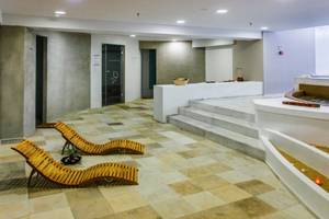 Spa-Bereich im Akti Palace Hotel mit zwei Holzliegen und einem Whirlpool.