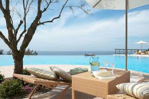 Strandszene mit Liegen und Pool im Ikos Oceania Hotel mit Blick auf das Meer.