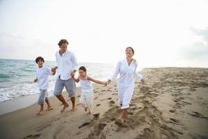 Eine Familie läuft am Strand, alle in weißen Kleidern, mit einem Lächeln auf den Gesichtern.