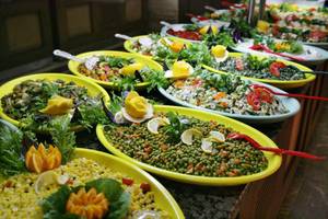 Buffet mit mehreren gelben Platten, gefüllt mit verschiedenen Gemüsesalaten und Beilagen.
