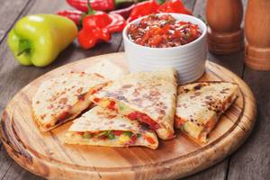 Gegrillte Quedillas mit Salsa und Paprika auf einem Holzteller.