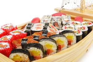 Verschiedene Sushi in einer hölzernen Bootsform präsentiert.