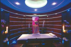 Spa-Behandlungsraum im Rhodes Bay Hotel & Spa mit einer Frau auf einer Liege und blauen Lichtern.