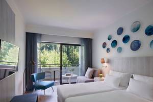 Schlafzimmer im Rhodes Bay Hotel & Spa mit zwei Betten, einem Balkon und modernen Dekorationen.