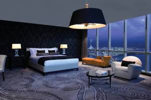 Innenansicht eines Conrad Abu Dhabi Etihad Towers Hotelzimmers mit großem Bett, Schreibtisch, Couch und Aussicht auf die Stadt.