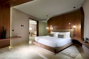 Schlafzimmer im TRS Coral Hotel mit einem großen Bett, Holzwänden und Beleuchtung.
