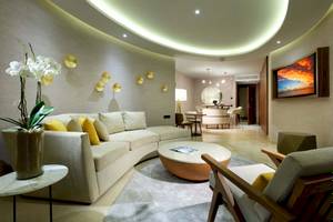 Innenansicht des Wohnzimmers im TRS Coral Hotel mit Rundsofa, Tisch und Fernseher.