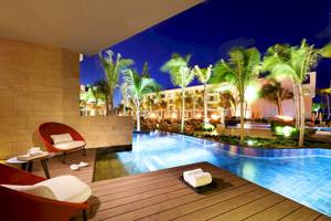 Poolbereich des TRS Coral Hotels bei Nacht mit roten Sesseln und Palmen