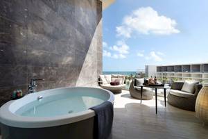 Balkon des TRS Coral Hotels mit Whirlpool und Meerblick, Möbeln und Flaschen auf einem Tisch.
