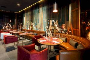 Innenansicht des Restaurants im TRS Coral Hotel mit gepolsterten Ledersofas, Tischdekorationen und Wandgemälden.
