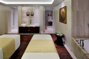 Spa-Behandlungsraum im Taj Dubai mit zwei Massagetischen, Badewanne und Dekor.