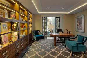 Innenansicht eines Zimmers im Taj Dubai Hotel mit Schreibtisch, Stühlen und Bücherregal.