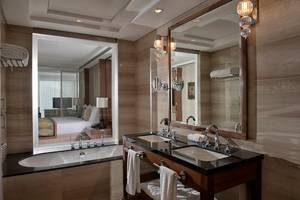 Badezimmer im Taj Dubai Hotel mit Badewanne, Spiegel und Waschbecken.